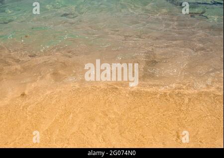 consistenza di acqua che corre onde sulla sabbia sulla spiaggia. Estate spiaggia sfondo. Sabbia e mare e cielo blu. Sabbia dorata con oceano blu Foto Stock