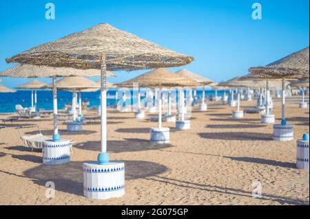 Spiaggia vuota mare sabbia cielo e giorno d'estate. Abstract bokeh estate e sfondo mare. Le persone si rilassano sui lettini sotto un ombrellone in riva al mare. Vacanze, vca Foto Stock