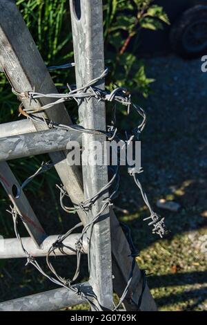 Filo spinato avvolto intorno ad un cancello di acciaio galvanizzato. Foto Stock