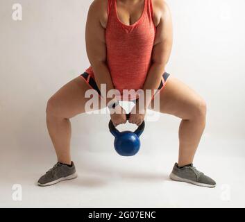 Donna bianca che suona squat sumo con kettlebell su sfondo bianco Foto Stock