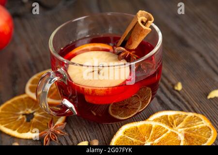 VIN brulé con spezie e frutta su un tavolo di legno marrone. Tradizionale bevanda calda natalizia con vino rosso, mele, arance e cannella Foto Stock