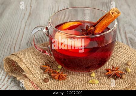 VIN brulé con spezie e frutta su sfondo ligneo. Tradizionale bevanda calda natalizia con vino rosso, mele, arance e cannella Foto Stock