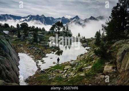 Cime del Parco Nazionale Aigüestortes, nei Pirenei, in un'alba nebbiosa estiva, visto da un lago vicino al rifugio Amitges (Pallars Sobirà, Cataluña) Foto Stock