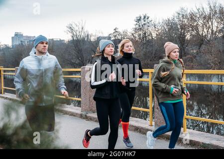 Sport giovani e di mezza età gruppi di persone che corrono nell'ambiente urbano. Gruppo di corridori nel parco in autunno primavera mattina. Gruppo di Foto Stock