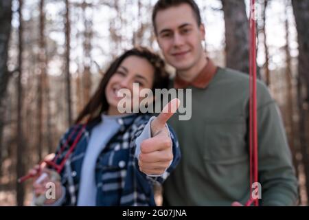 donna felice offuscata che mostra il pollice in su vicino amico volontario nella foresta Foto Stock