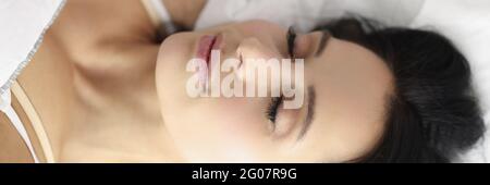 Giovane bruna caucasica che dorme nel letto bianco Foto Stock