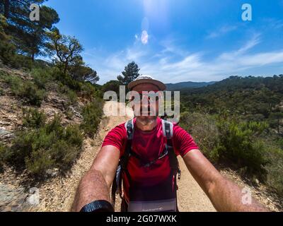 Uomo che prende selfie mentre cammina lungo il percorso costiero spagnolo della Costa Brava, conosciuto anche come GR92 Cami de Ronda, passando nell'entroterra vicino Tossa de Mar Foto Stock