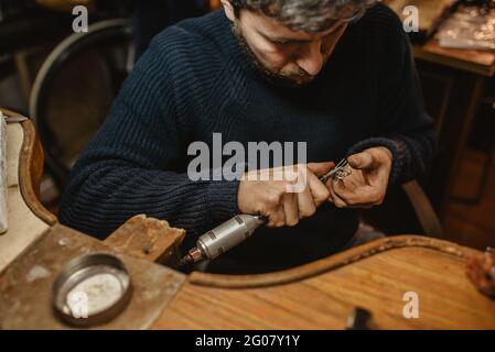 Basso angolo di sorridente giovane femmina in spogliatore e occhiali da sole con capelli lunghi che volano nel vento appoggiandosi su recinzione guardando la macchina fotografica contro cielo nuvoloso An Foto Stock