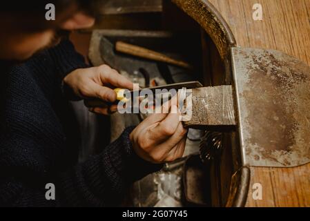 Anonimo Jeweler maschio usando la lima per modellare l'anello metallico sopra banco da lavoro in officina Foto Stock