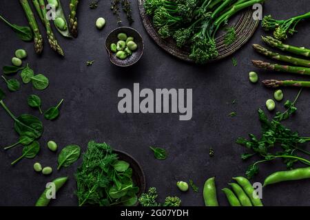 Composizione aerea di vegetazione vegetariana biologica sana di grappoli e baccelli, foglie e fagioli sul tavolo Foto Stock