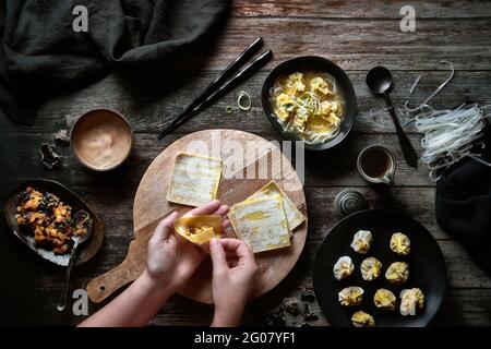 Vista dall'alto dell'anonima Donna che prepara zuppa di wonton su un tavolo di legno Foto Stock