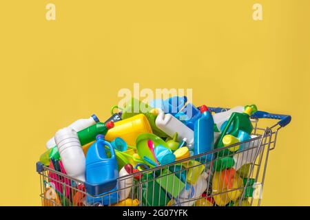 Carrello di diversi pacchetti di plastica colorata su sfondo giallo Foto Stock