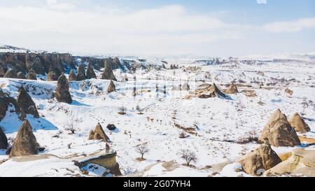 Da sopra il corpo pieno irriconoscibile coppia turisti in piedi sulla pietra e ammirando le incredibili vedute del paesaggio innevato sul cielo blu senza nuvole su un moun innevato Foto Stock