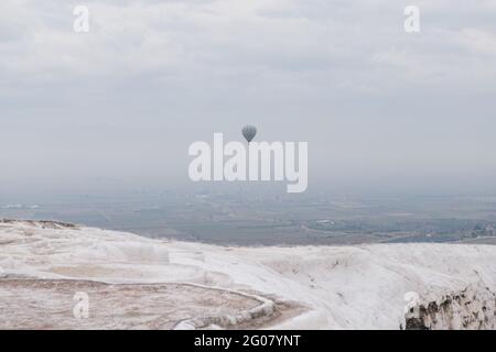 Vista dalla montagna salina di mongolfiera che vola in grigio cielo sulla campagna in nebbia fitta in tempo coperto Turchia Foto Stock