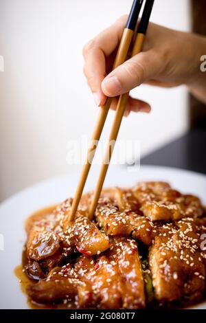 Preparato gustoso pollo piccante su piatto bianco su tavolo di legno In un ristorante asiatico Foto Stock