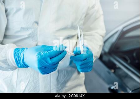 Biologo con guanti protettivi che esegue un test del coronavirus su un persona in auto Foto Stock