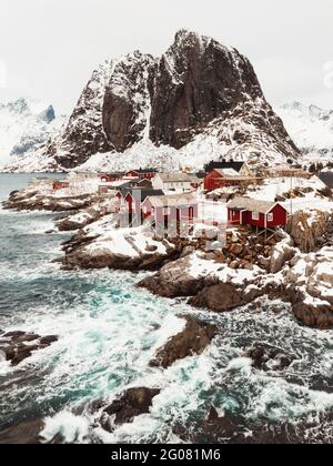 Da sopra le cabine vista aerea situate sulla catena montuosa costa innevata sulle isole Lofoten, Norvegia Foto Stock