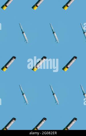 Vista dall'alto del mosaico o del modello di esami del sangue positivi e della siringa su sfondo blu. Foto Stock