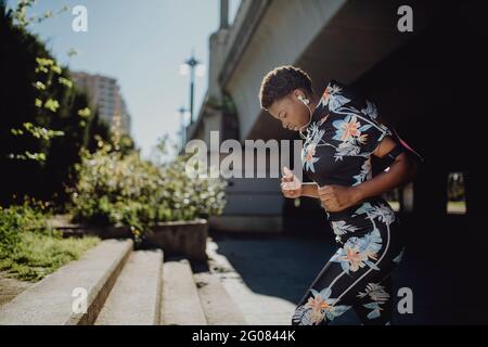 Giovane fitness African American Woman running mentre si trova sulla strada cittadina Foto Stock