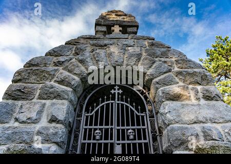 Porta di ferro con teschi come ingresso a un monumento in pietra a Mackat, Serbia Foto Stock