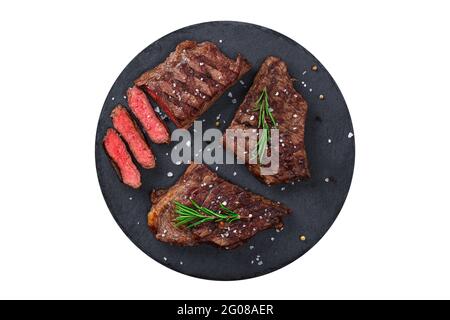 Tagliata media rara bistecca alla griglia su tagliere con rosmarino e spezie, isolato su sfondo bianco, vista dall'alto. Carne fresca alla griglia. Bistecca di manzo alla griglia. Foto Stock