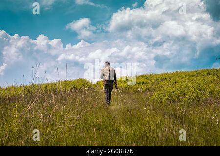 Giovane cacciatore che sale su una collina alla ricerca di preda Foto Stock