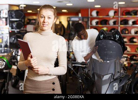 donna che si trova in piedi in un negozio di motociclette Foto Stock