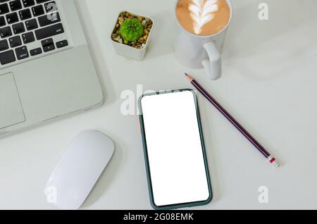 Vista dall'alto mock-up smartphone bianco schermo vuoto e matita caffè tazza mouse computer portatile computer portatile piatto su scrivania. Foto Stock