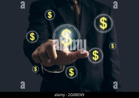 La mano dell'uomo di affari sta indicando o premendo il tasto con il simbolo dell'icona finanziaria del dollaro sullo schermo virtuale. Concetto aziendale e tecnologia digitale Foto Stock