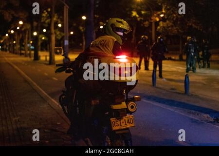 Medellin, Colombia il 31 maggio 2021. Un poliziotto guarda indietro dal suo motociclo ai manifestanti come un gruppo di manifestanti agganciati scontri con la polizia colombiana in rivolta (ESMAD) a Medellin, Colombia durante le proteste contro il governo contro la riforma fiscale e sanitaria del Presidente Ivan Duque e la brutalità e i disordini della polizia che lasciano almeno 70 morti nel mese scorso, a Medellin, Colombia, il 31 maggio 2021. Foto Stock