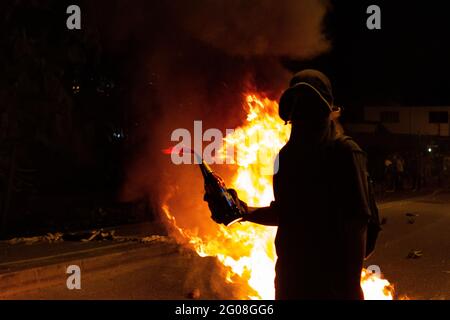 Medellin, Antioquia, Colombia. 31 maggio 2021. Un dimostratore si trova di fronte a un incendio con una bomba Molotov, in quanto un gruppo di dimostranti incappucciati si scontra con la polizia colombiana in rivolta (ESMAD) a Medellin, Colombia durante le proteste contro il governo contro la riforma fiscale e sanitaria del Presidente Ivan Duque e la brutalità e i disordini della polizia che lasciano almeno 70 morti nel mese scorso, a Medellin, Colombia, il 31 maggio 2021. Credit: Meyer Juana/LongVisual/ZUMA Wire/Alamy Live News Foto Stock