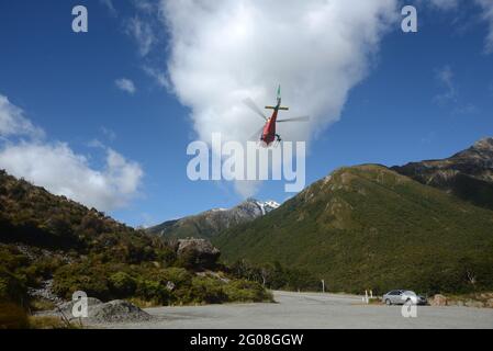 ARTHURS PASS, NUOVA ZELANDA, 2021-01-29: Un elicottero dipinto di colori vivaci decollo da un parcheggio nel Parco Nazionale di Arthur's Pass, Nuova Zelanda Foto Stock