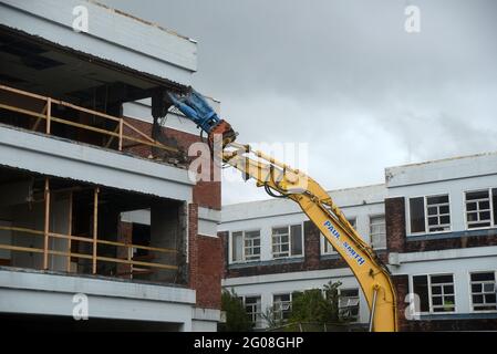 GREYMOUTH, NUOVA ZELANDA, 19 gennaio 2021: Un escavatore utilizza un attacco a artiglio per demolire il vecchio edificio ospedaliero a Greymouth, Nuova Zelanda, gennaio Foto Stock