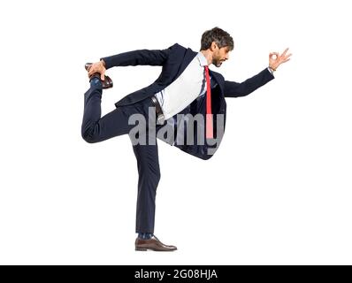Un uomo d'affari intelligente di media età in una tuta facendo una ballerina di yoga posa l'equilibrio su una gamba in un tratto in avanti isolato su uno sfondo bianco dello studio Foto Stock