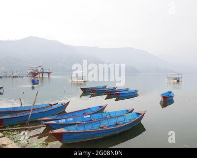 Barca in canoa di legno di gente nepalese che galleggia in Phewa tal o Fewa Freshwater Lake servizio di attesa gente nepalese e viaggiatore straniero che va a canottaggio relax Foto Stock