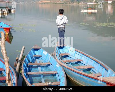 Barca in canoa di legno di gente nepalese che galleggia in Phewa tal o Fewa Freshwater Lake servizio di attesa gente nepalese e viaggiatore straniero che va a canottaggio relax Foto Stock