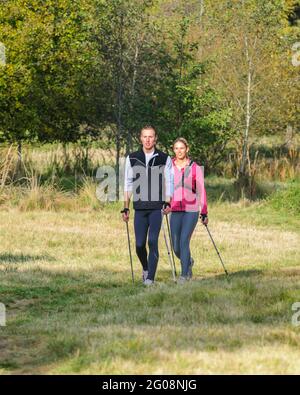 Giovane coppia che fa Nordic Walking esercizio in tempo di falltime Foto Stock