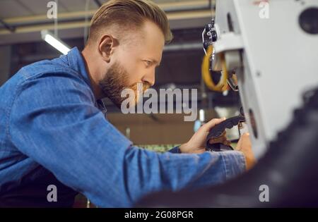 Calzaturiera che fa un dettaglio per nuove calzature su una macchina da cucire industriale Foto Stock