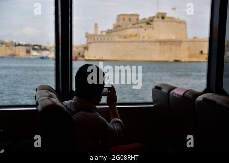 Valletta, Malta. 1 giugno 2021. Un passeggero scatta una foto fuori dalla finestra all'arrivo a la Valletta Harbour, Malta, 1 giugno 2021. Due catamarani che forniscono un servizio veloce di traghetto tra la Valletta, capitale di Malta, e l'isola di Gozo, hanno fatto il loro primo viaggio il 1 giugno, quando Malta ha riaperto il suo settore turistico nello stesso giorno. Credit: Jonathan Borg/Xinhua/Alamy Live News Foto Stock