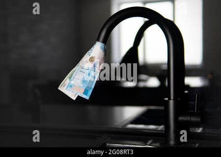 rubinetto dell'acqua che sputano le fatture del dollaro americano. Approvvigionamento di acqua costoso. Il concetto di aumentare il prezzo dei servizi pubblici per la popolazione. Costoso Foto Stock