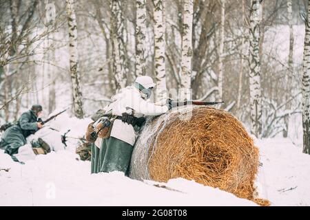 Re-enactor vestito come il soldato tedesco di fanteria Wehrmacht nella seconda guerra mondiale che mira la fucile da rotolo di fieno al giorno d'inverno. Rievocazione storica. SECONDA GUERRA MONDIALE Foto Stock