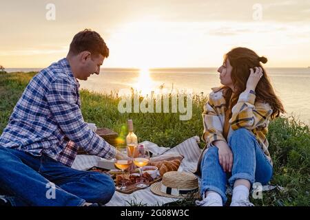 Coppia che ha pic-nic su prato verde con una vista mare Foto Stock