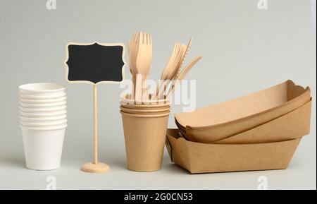 tazze di carta bianca, marrone, monouso, piastre rettangolari e forcelle di legno su sfondo grigio. Zero sprechi, nessuna plastica Foto Stock