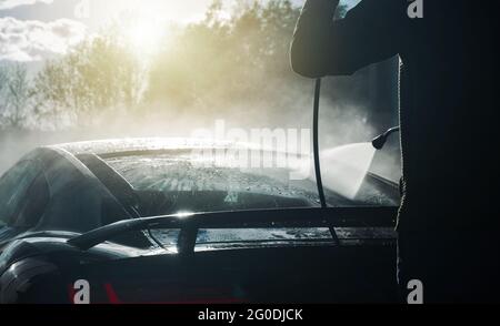 Uomini caucasici nel suo 40s pressione lavando il suo tetto esotico di veicolo di prestazione in un edificio di lavaggio di automobile. Tema automobilistico. Foto Stock