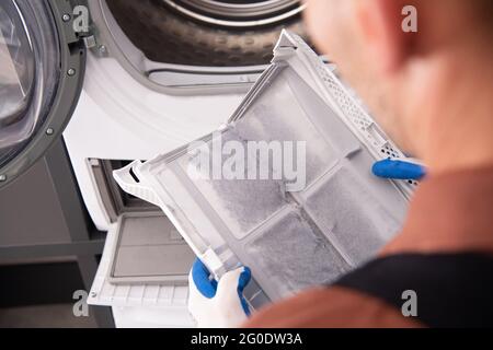 Filtro lavatrice e asciugatrice coperto da sporcizia. Pulizia del filtro eseguita dal tecnico degli elettrodomestici. Foto Stock
