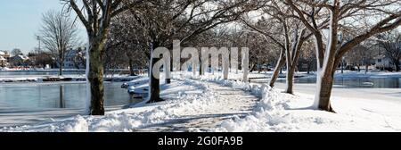 Un sentiero innevato alberato è una passeggiata a stoppa tra i due laghi di Argyle Park a Babylon Village New York. Foto Stock