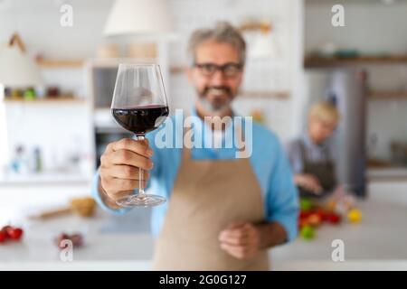 Felice coppia senior che cucinano insieme e bevono vino a casa cucina Foto Stock