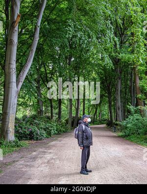 Berlino, Mitte, Tiergarten Parco pubblico in tarda primavera. Uomo anziano che indossa la maschera facciale cammina nel parco durante Covid Pandmic Foto Stock