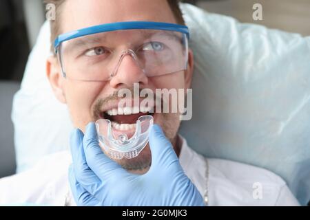 Dentista che cerca sul boccaglio per paziente uomo Foto Stock