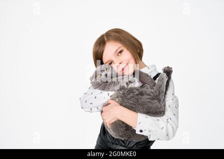 La bambina caucasica tiene il suo gatto tra le braccia Foto Stock